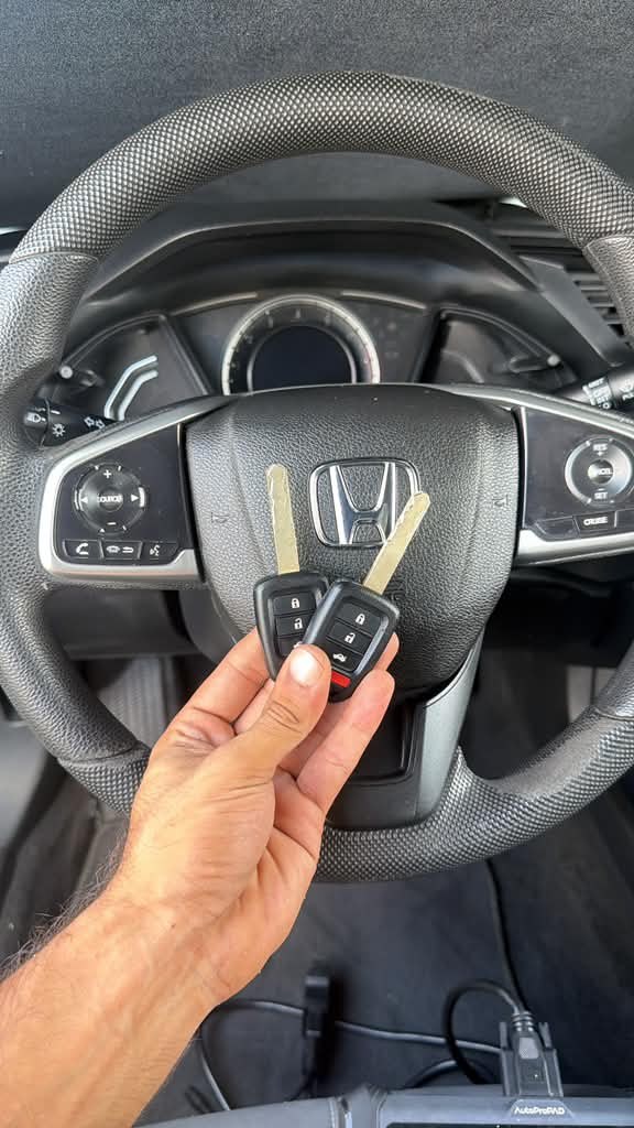 Honda key fob in front of a Honda steering wheel